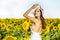 Woman poses in the agricultural field with sunflower on a sunny summer day