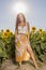 Woman poses in the agricultural field with sunflower on a sunny summer day