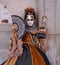 Woman poses in ornate, detailed costume, mask and hat, at the Doges Palace, St Mark`s Square during during Venice Carnival, Italy