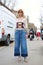 Woman poses for photographers with blue jeans and decorated sweater before Fendi fashion show, Milan Fashion