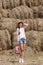 Woman posing against a stack of hay