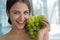 Woman posing with a bunch of grapes and smiling.