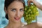 Woman posing with a bunch of grapes and smiling.