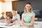 A woman is posing in her kitchen. Behind her, her mother and her daughter. They are busy preparing homemade cookies