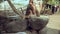 Woman pounding food using a wooden pestle with handle in a large stone mortar