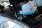 Woman pouring antifreeze from plastic canister into windshield washer fluid reservoir, closeup