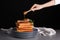 Woman pouring chicken drumstick and waffles with honey against dark background