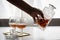 Woman pouring and drinking brandy of lead crystal bottle in cognac snifter glasses