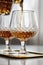 Woman pouring and drinking brandy of lead crystal bottle in cognac snifter glasses