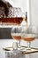 Woman pouring and drinking brandy of lead crystal bottle in cognac snifter glasses