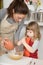 Woman pouring flour in bowl and child whipping