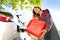 Woman pouring fuel into gas tank of a car from can