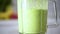 Woman pouring healthy green smoothie on glass. Detox and healthy life concept. Vegan, vegetarian diet