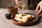 Woman pouring honey onto thin pancakes with berries