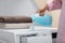 Woman pouring laundry detergent into cap on washing machine indoors