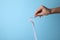 Woman pouring laundry detergent from  container against blue background, closeup. Space for text