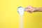 Woman pouring laundry powder from measuring scoop on yellow background