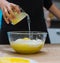 Woman pouring lemon juice in a dough