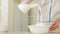 Woman pouring milk into bowl of flour