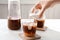 Woman pouring milk into glass with cold brew coffee