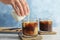 Woman pouring milk into glass with cold brew coffee