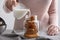 Woman pouring milk into mason jar with coffee ice cubes on table