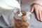 Woman pouring milk into mason jar with coffee ice cubes on table, closeup