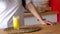 Woman pouring orange lemonade into glass. Close up of filling transparent glass with soda in kitchen.