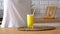 Woman pouring orange lemonade into glass. Close up of filling transparent glass with soda in kitchen.