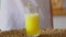 Woman pouring orange lemonade into glass. Close up of filling transparent glass with soda in kitchen.