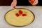 Woman pouring pizza marinara on raw dough