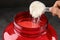 Woman pouring protein powder from measuring scoop into jar