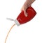 Woman pouring tasty ketchup from bottle on white background, closeup