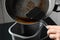 Woman pouring used cooking oil from frying pan into container, closeup