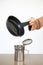 Woman pouring used cooking oil from an old frying pan into a metal cooking container