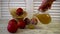 A woman pours apple juice from a jug into a glass. Nearby are apples on the table