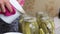 A woman pours boiling marinade over cucumbers in jars. Pickling cucumbers at home. Vegetable harvest conservation. Close-up shot