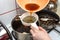 The woman pours the decoction of the mushroom soup through a plastic strainer.