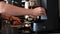 A woman pours ground coffee beans to make a cappuccino in a coffee machine. Close plan of barista hands preparing tonic