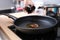 Woman pours olive oil into hot frying pan closeup