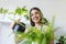 woman pours water into a flower pot, she cares for house plants. Young woman watering her plants