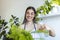 woman pours water into a flower pot, she cares for house plants. Young woman watering her plants