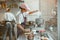 Woman pours wheat flour into container on digital scales with colleague in bakery