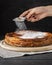 Woman powdering cheese cake with icing sugar