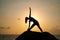 The woman practices yoga at dawn, there is an asana on a stone, dawn and an image of the girl, to enjoy dawn, to be happy with lif