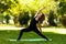 Woman practices yoga in morning in park in fresh air. Exalted Crescent Lunge pose