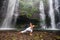 Woman practices yoga near Sekumpul waterfall in Bali, Indonesia