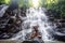 Woman practices yoga near waterfall in Bali, Indonesia