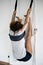 Woman practicing iyengar yoga using wall ropes in studio