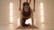 Woman practicing yoga in aero yoga studio. Yoga trainer standing on hands at mat
